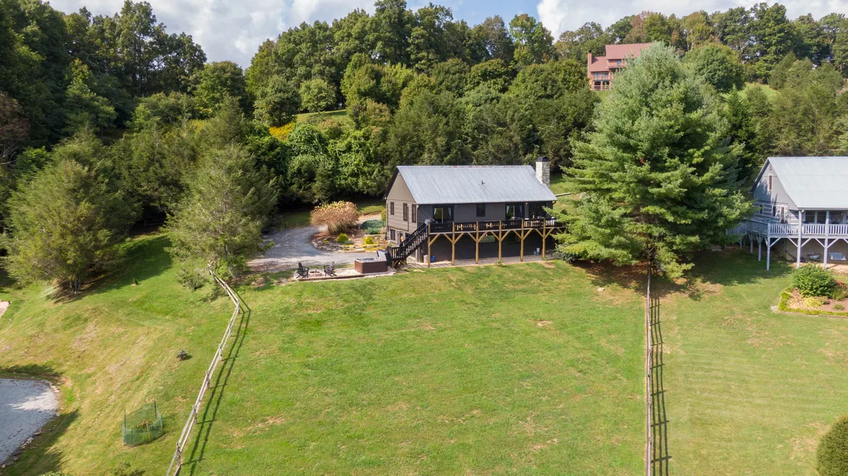 This image shows the exterior of Horse Valley Lodge, including the spacious deck and surrounding trees, with a grassy area that invites outdoor gatherings. The setting captures the tranquility of the mountain environment and the ample outdoor space available for group activities and socializing.