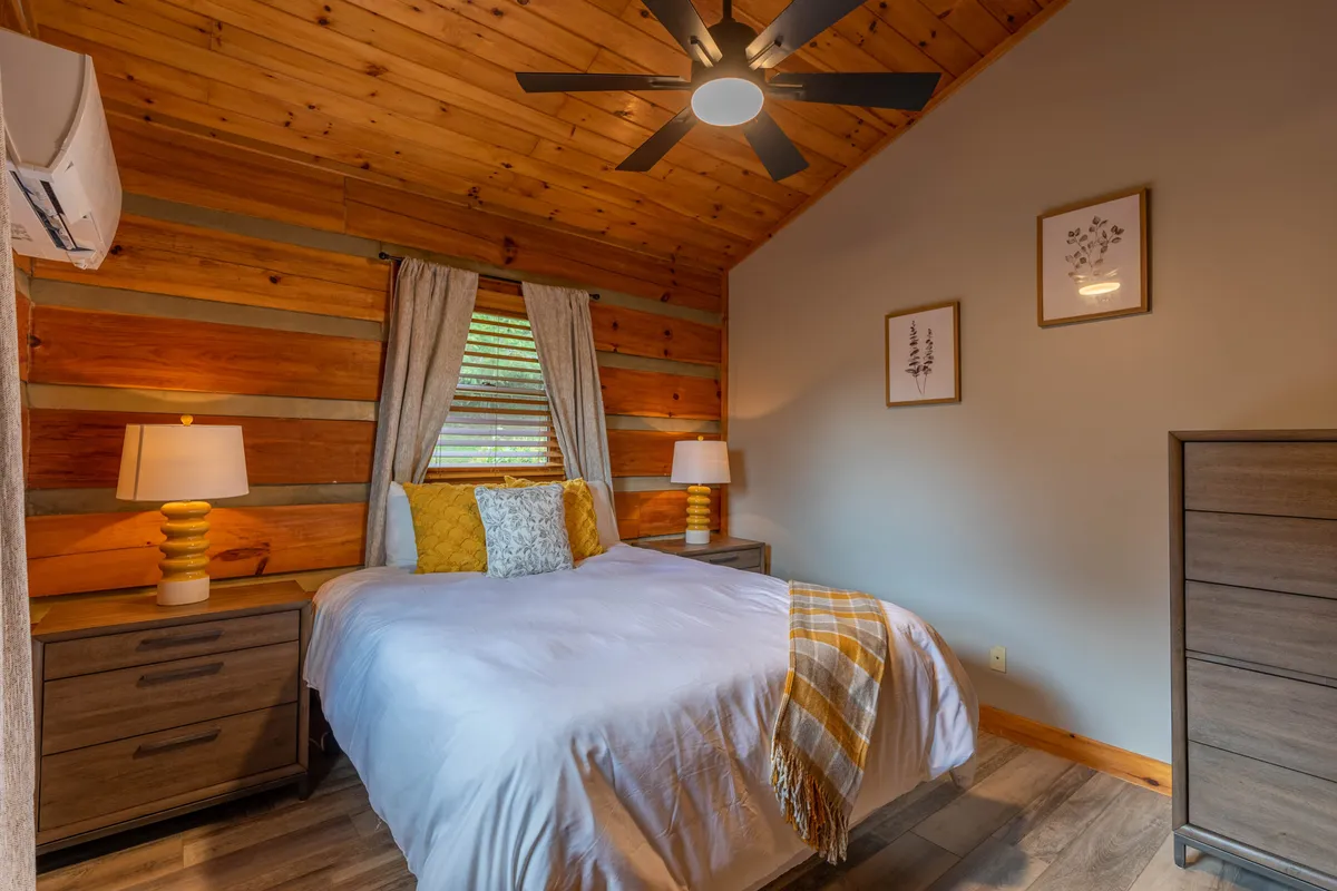 A cozy bedroom with a bed adorned with decorative pillows, nightstands with lamps for reading, and a charming wooden ceiling. The inviting ambiance and soft lighting create a haven for relaxation and privacy, suitable for additional bedrooms spread across the home.