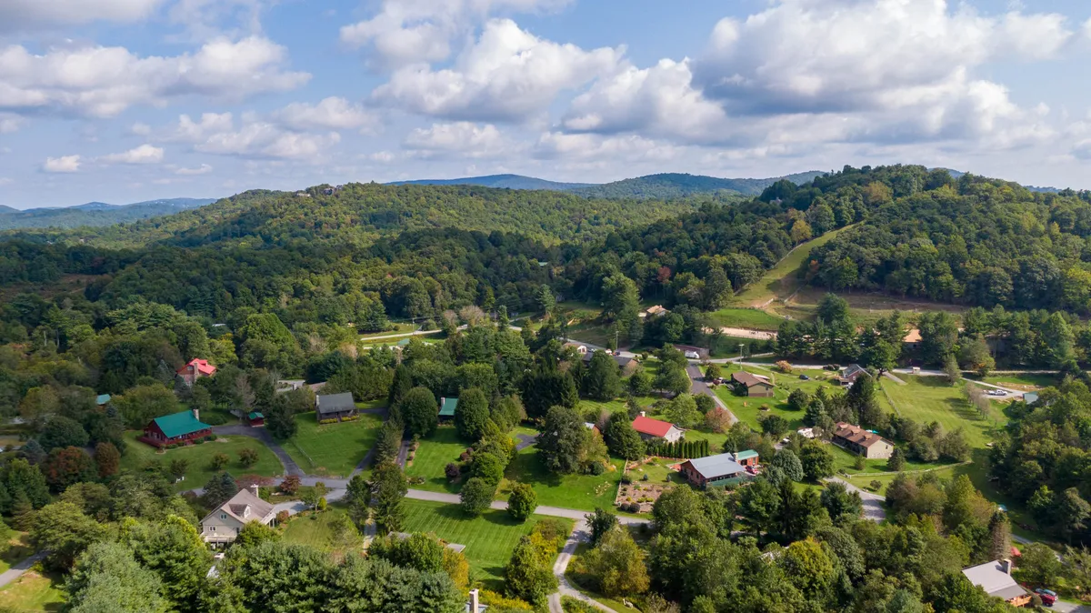 A wide, scenic view of rolling hills, scattered homes, and lush greenery—iconic of the Blue Ridge region. The landscape evokes a sense of adventure, exploration, and accessibility to nature's playground.