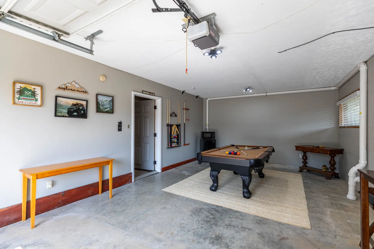 A close-up view of the pool table with decorative wall art and a small wooden table nearby. The scene feels playful and welcoming, emphasizing both activity and relaxation.